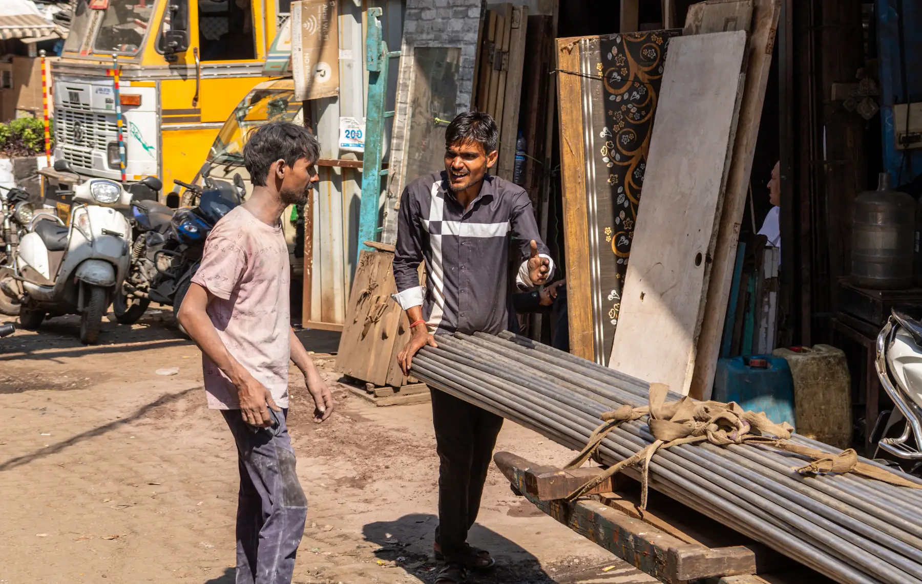 Two men moving steel pipes outside a trading shop in Girgaon, Mumbai